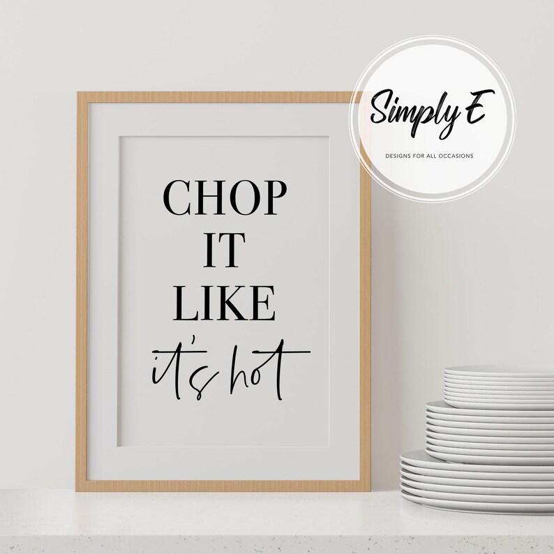 May include: A framed print with the text "CHOP IT LIKE it's hot" in black lettering on a white background. The frame is light brown wood.