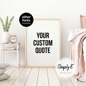 K&ouml;nnte beinhalten: Ein gerahmter Druck mit dem Text "YOUR CUSTOM QUOTE" in fetter, schwarzer Schrift. Der Rahmen ist goldfarben. Links befindet sich ein kleiner Tisch mit einer Vase, einer Uhr und B&uuml;chern. Das Bild enth&auml;lt auch den Text "other fonts available" und das Logo "Simply E".