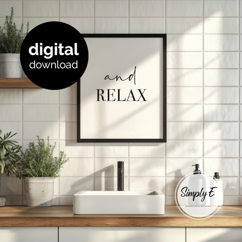 May include: A black framed wall art print featuring the text and relax in a combination of script and serif fonts on a cream background. The print is displayed above a white rectangular bathroom sink with a black faucet and two potted plants.