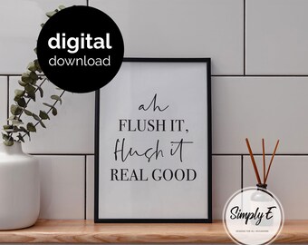 May include: A black framed wall art print featuring the black text "ah FLUSH IT, Flush it REAL GOOD" on a white background. The print is displayed on a wooden shelf next to a white vase with green foliage and a reed diffuser with brown sticks.