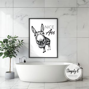 May include: Black framed wall art featuring a grayscale illustration of a donkey with the text "NICE Ass". The artwork is a humorous piece, suitable for bathroom or home decor. The donkey is drawn in a realistic style.
