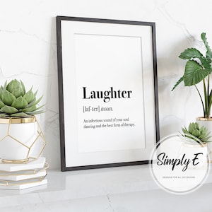 Puede incluir: Impresi&oacute;n enmarcada en negro con la definici&oacute;n de "Risa" en texto negro. La impresi&oacute;n se muestra sobre una superficie blanca con plantas decorativas en macetas blancas y doradas. La imagen incluye el logotipo de Simply E.