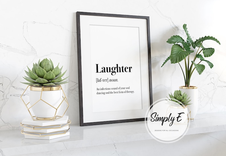 Puede incluir: Impresi&oacute;n enmarcada en negro con la definici&oacute;n de "Risa" en texto negro. La impresi&oacute;n se muestra sobre una superficie blanca con plantas decorativas en macetas blancas y doradas. La imagen incluye el logotipo de Simply E.