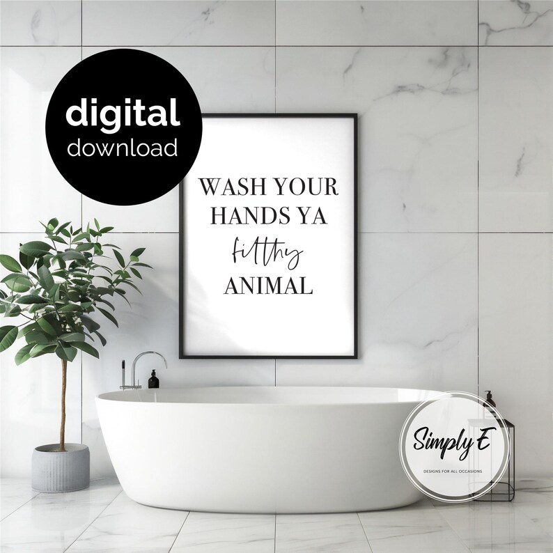 May include: A rectangular black-framed wall art print featuring the black text WASH YOUR HANDS YA filthy ANIMAL on a white background. The print is displayed above a white bathtub. A black circular badge with the white text digital download is visible.