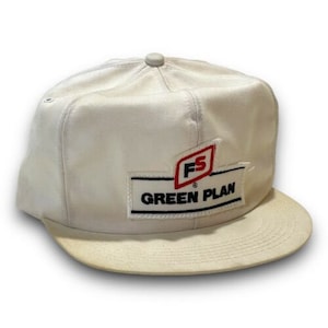 Puede incluir: Gorra de béisbol blanca con un logotipo en blanco y negro que dice "Green Plan" y un logotipo en rojo y blanco que dice "FS".