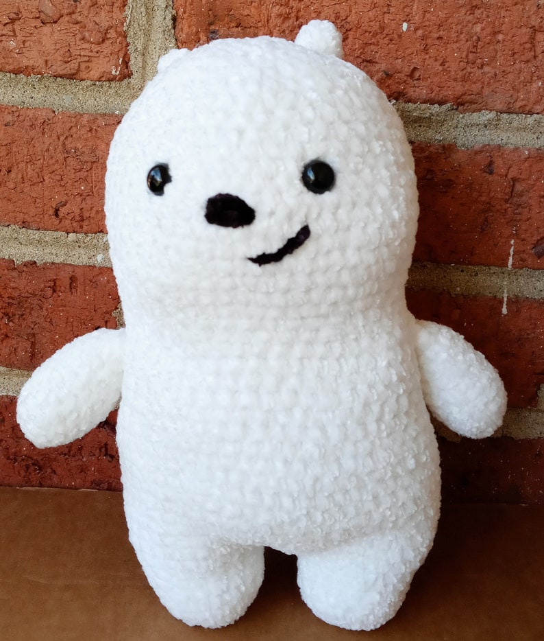 May include: White crocheted plush toy shaped like a bear with black eyes and a black nose. The bear has a smiling expression.