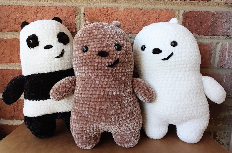 May include: Three crocheted plush toys: a black and white panda bear, a brown bear, and a white polar bear. The bears are all smiling and have black eyes.