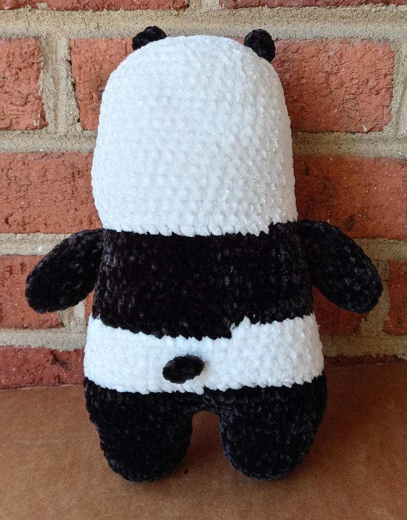 May include: A black and white crocheted panda plush toy. The panda has a white face and black ears, arms, legs, and a black patch around its eyes.