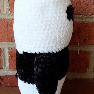 May include: A black and white crocheted panda plush toy. The panda has a black nose and eyes and a black pom-pom on its head.