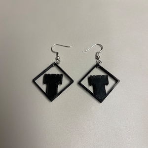 May include: A pair of black earrings with a square design featuring a silhouette of a tower inside each square.