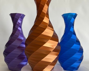 Może przedstawiać: Trzy ceramiczne wazony o geometrycznym, skręconym wzorze. Wazony są w odcieniach fioletu, miedzi i błękitu.