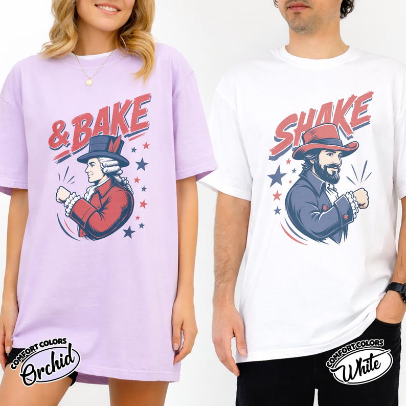 May include: A light purple t-shirt featuring a graphic of a historical figure in a red coat and top hat with the text & BAKE, and a white t-shirt featuring a graphic of a bearded figure in a red hat and blue coat with the text SHAKE.