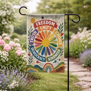 May include: A rectangular garden flag featuring a central sun graphic with multicolored rays. Surrounding the sun are the words Freedom, Unity, Choice, Kindness, Democracy, and Truth. The design includes leaves, stars, hearts, and a rainbow.