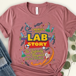 May include: A dusty rose t-shirt featuring a colorful graphic design. The design includes a microscope, beakers, DNA strands, and a rocket ship. Text on the shirt reads "LAB WEEK 2026 LAB STORY To Infinity and Beyond for Our Patients."