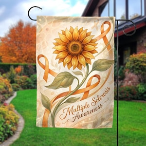 May include: A garden flag featuring a large sunflower with orange ribbons and the words "Multiple Sclerosis Awareness." The flag has a beige background with a floral design and is displayed outdoors.