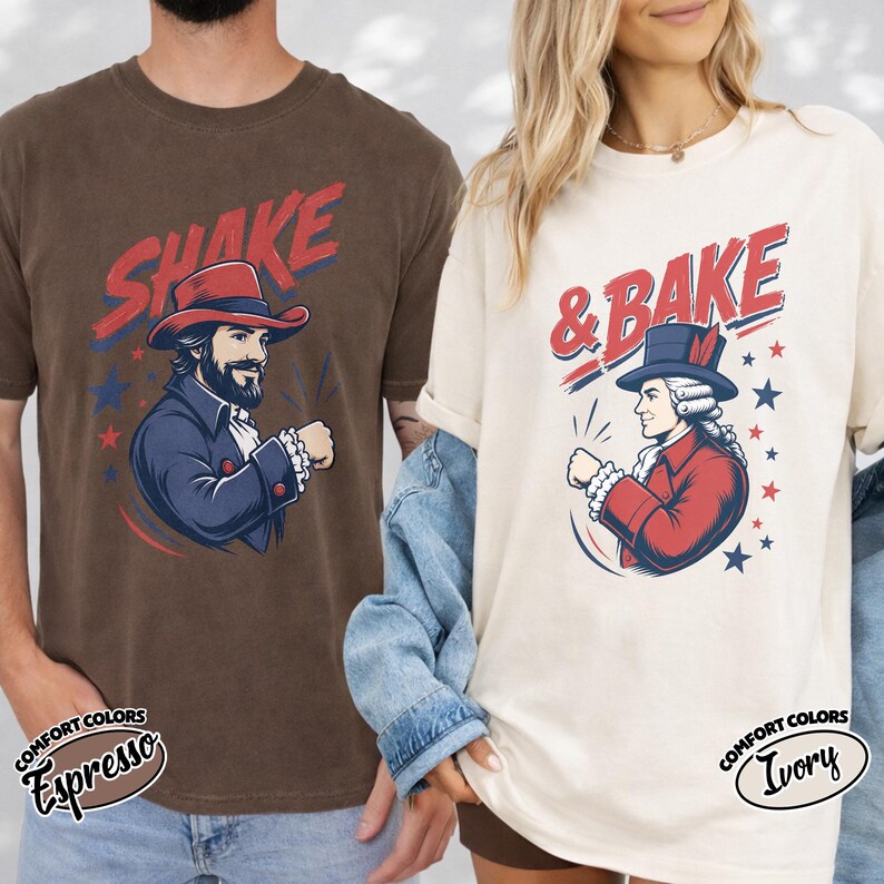 May include: A brown t-shirt with the text SHAKE and a graphic of a man in a colonial hat, and an ivory t-shirt with the text & BAKE and a graphic of a person in a colonial hat. Both shirts feature red, white, and blue star accents.