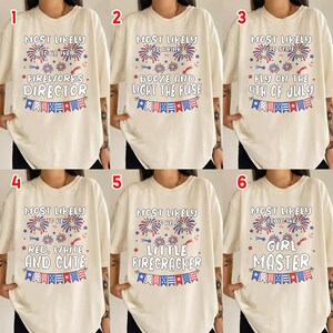 May include: Six off-white t-shirts featuring red and blue firework graphics and patriotic bunting. Each shirt displays unique text: Most Likely To Be The Fireworks Director, Booze And Light The Fuse, Stay Fly On The 4th Of July, Red, White And Cute, A Little Firecracker, or Girl Master.