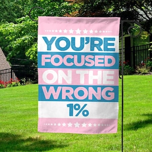 May include: A pink and blue garden flag with white stars and the text "You're focused on the wrong 1%".