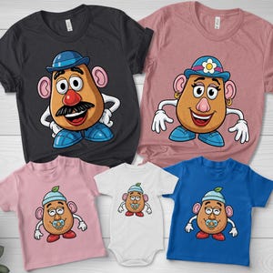 May include: A collection of family t-shirts and a baby onesie featuring a cartoon potato character. The shirts are in black, pink, and blue, with the potato character wearing a hat and shoes. The onesie is white.