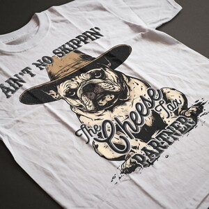May include: White t-shirt featuring a bulldog wearing a cowboy hat. The graphic includes the text "Ain't No Skippin'" above the dog and "The Cheese Tax Partner" below. The design is in black and tan.