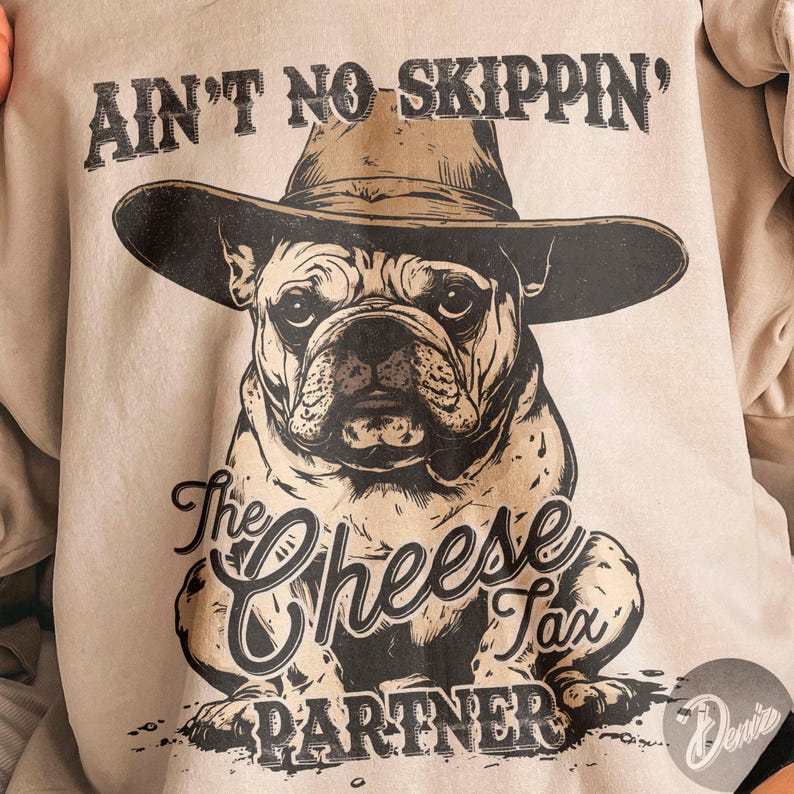 May include: A light beige sweatshirt featuring a bulldog wearing a cowboy hat. The graphic includes the text "AIN'T NO SKIPPIN'" above the dog and "The Cheese Tax Partner" below. The design is in black and brown.
