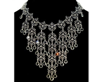 May include: A silver necklace with a cascading design of crystal-like stones and intricate floral patterns.