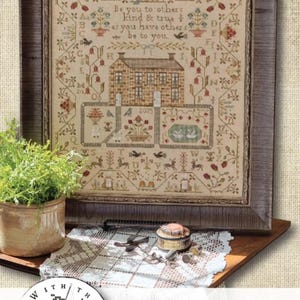 May include: A framed cross-stitch sampler featuring a central stone house, alphabet letters, floral motifs, and the text: Be you to others kind & true as you have others be to you. The design includes birds, deer, and the year 2025 in a muted color palette.