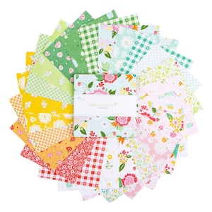 May include: A collection of colorful fabric squares arranged in a circular pattern. The squares feature various floral, gingham, and strawberry patterns in shades of green, yellow, pink, and red. A white label with text is visible in the center.