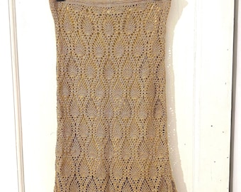 May include: A gold-colored, sleeveless tube top featuring an intricate, repeating pineapple-shaped crochet pattern. The garment has a straight, finished neckline and a matching hem, showcasing a delicate, open-work knit texture throughout the piece.