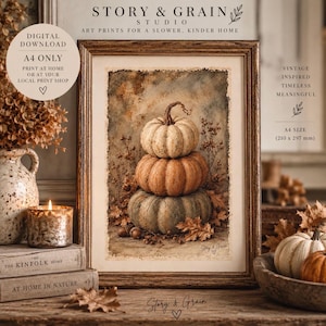 May include: A framed art print featuring a vertical stack of three pumpkins in shades of cream, orange, and muted green, surrounded by dried foliage. The text reads STORY & GRAIN STUDIO, DIGITAL DOWNLOAD, A4 ONLY, and VINTAGE INSPIRED TIMELESS MEANINGFUL.