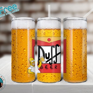 Op de afbeelding: Drie roestvrijstalen bekers met deksels en rietjes. De bekers zijn gevuld met een gele vloeistof die eruitziet als bier. De middelste beker heeft een afbeelding van een cartoonfiguur dat een blikje bier vasthoudt met de tekst "Duff Beer" erop.