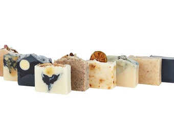 May include: An assortment of handmade soap bars in various colors and designs. The soaps feature natural ingredients and decorative elements like dried citrus and flower petals. Each bar is unique, with a focus on natural skincare.