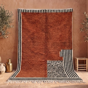 May include: A rectangular area rug featuring a deep rust-orange shaggy texture, accented by bold black and white vertical stripes along the left and bottom edges, and a distinct black and white speckled rectangular block in the lower right corner.