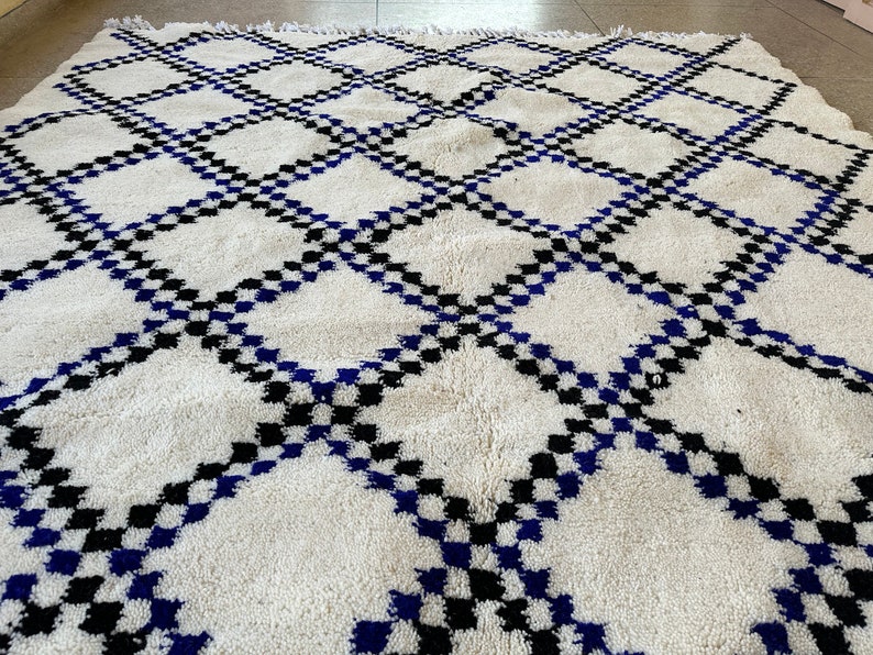 May include: White, blue, and black Moroccan rug with a geometric diamond pattern.