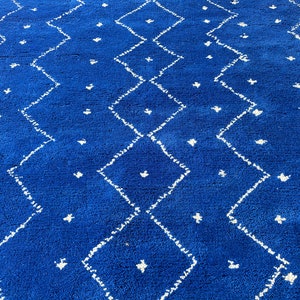 Puede incluir: Una alfombra azul y blanca con un dise&ntilde;o de diamantes. La alfombra est&aacute; hecha de un material suave y mullido.