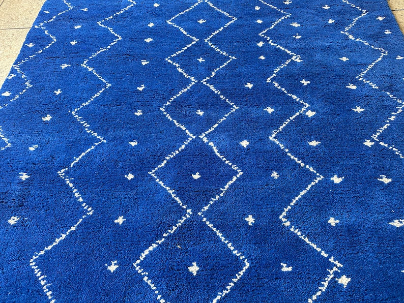 Puede incluir: Una alfombra azul y blanca con un dise&ntilde;o de diamantes. La alfombra est&aacute; hecha de un material suave y mullido.