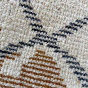 May include: Close-up of a woven rug with a geometric pattern in shades of brown, white, and gray.