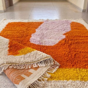 Bright orange wool rug with shag texture and artistic pattern in a contemporary home setting
