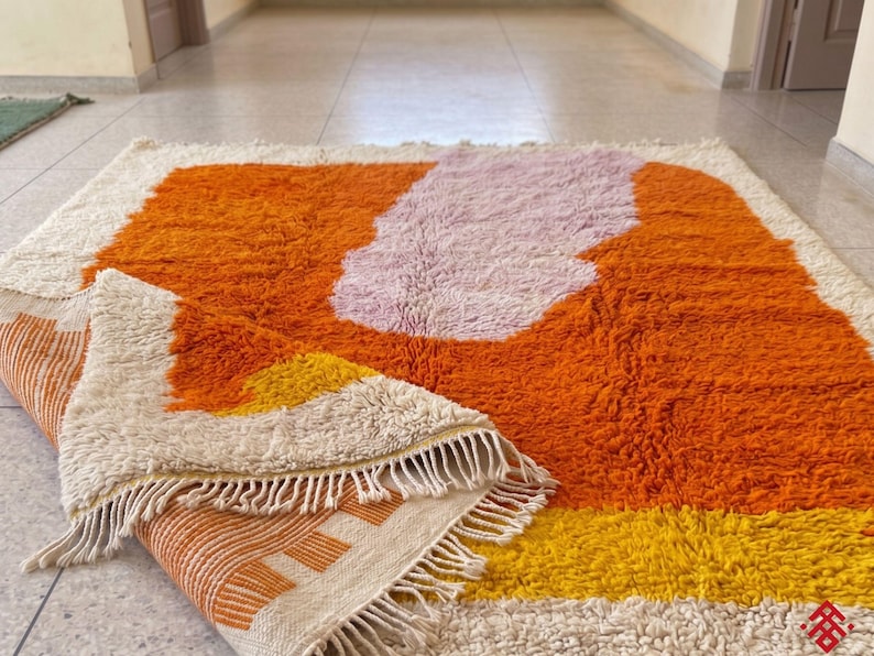 Bright orange wool rug with shag texture and artistic pattern in a contemporary home setting