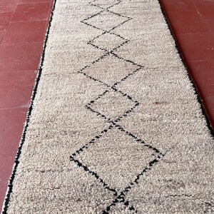 May include: A white rug with a black diamond pattern. The rug is made of a soft, fluffy material.
