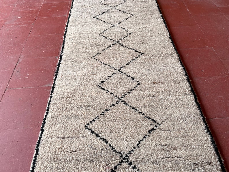 May include: A white rug with a black diamond pattern. The rug is made of a soft, fluffy material.