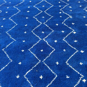 Puede incluir: Una alfombra azul con un patr&oacute;n de diamantes blancos. La alfombra tiene una textura suave y esponjosa.