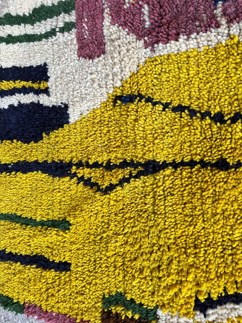Puede incluir: Primer plano de una alfombra colorida con un patr&oacute;n amarillo, negro, blanco, verde y rosa. La alfombra est&aacute; hecha de un material suave y esponjoso.