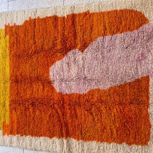 Modern living space featuring a bold orange Moroccan rug with abstract geometric patterns