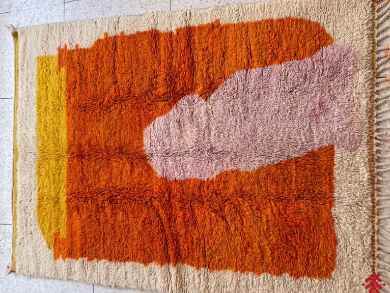 Modern living space featuring a bold orange Moroccan rug with abstract geometric patterns