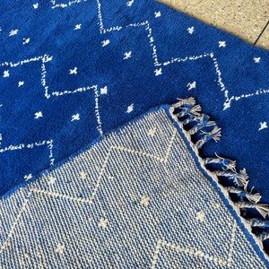 Puede incluir: Dos alfombras azules y blancas con flecos. La alfombra de arriba tiene un patr&oacute;n geom&eacute;trico y la alfombra de abajo tiene un patr&oacute;n m&aacute;s intrincado.