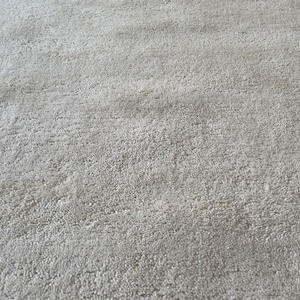 May include: Close-up of a light gray, textured rug with a subtle pattern. The rug has a soft, plush feel.