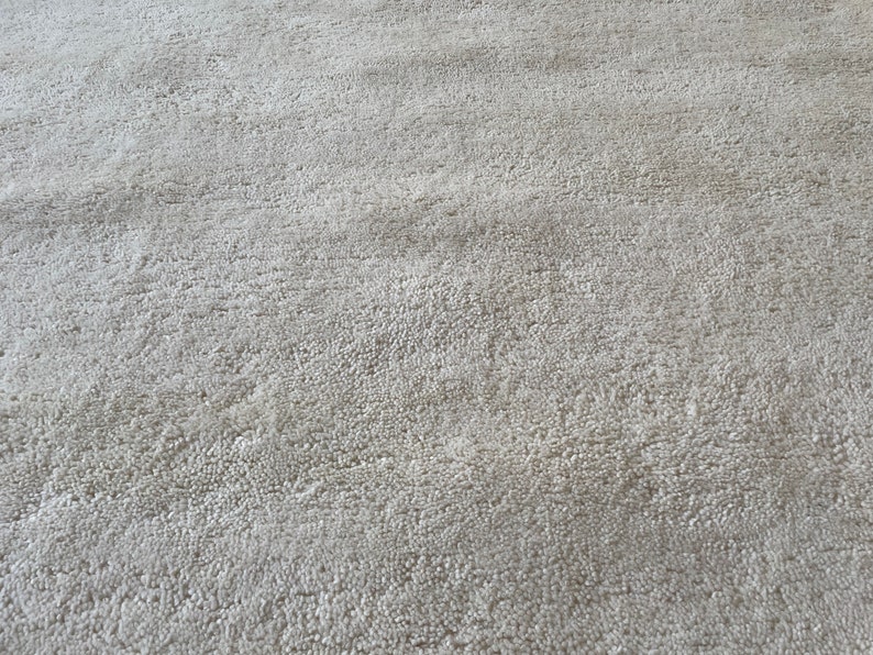 May include: Close-up of a light gray, textured rug with a subtle pattern. The rug has a soft, plush feel.