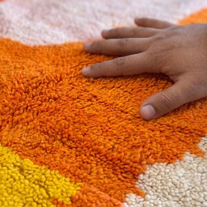 Orange Berber wool rug with soft shag texture and bold abstract design on a neutral floor setting