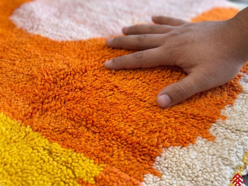 Orange Berber wool rug with soft shag texture and bold abstract design on a neutral floor setting